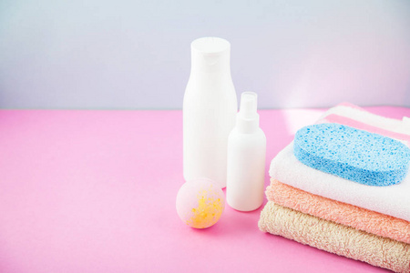 卫浴配件毛巾和洗发水, 沐浴泡沫, 奶油上的光, 明亮的蓝色和粉红色背景的概念, 照顾自己, 你的身体。复制空间