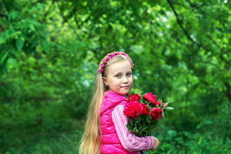 一个可爱的小女孩的肖像在公园里有一束牡丹花