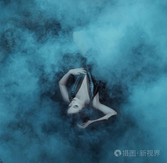 黑暗的吸血鬼女王躺在她的黑色礼服上的雾拥抱与深领口.