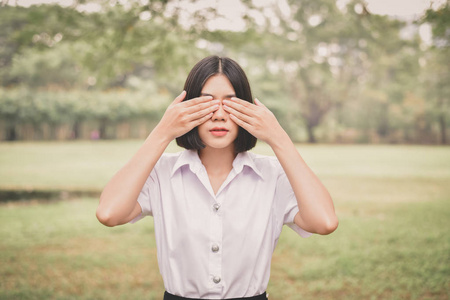 教育理念。美丽的亚洲小女孩正在认真思考。美丽的亚洲学生在花园里思考。美丽的年轻学生在花园里头疼