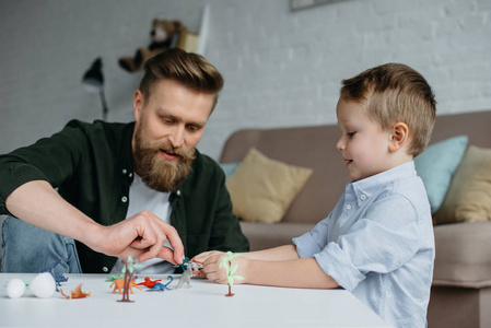 父亲和可爱的小儿子玩各种玩具恐龙在家一起