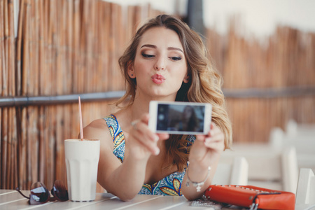 年轻女子在巴黎街头咖啡馆里采取与智能手机的自画像 拍照