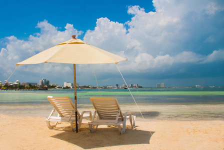 在坎昆海滩上为游客准备的太阳躺椅和白色雨伞。墨西哥