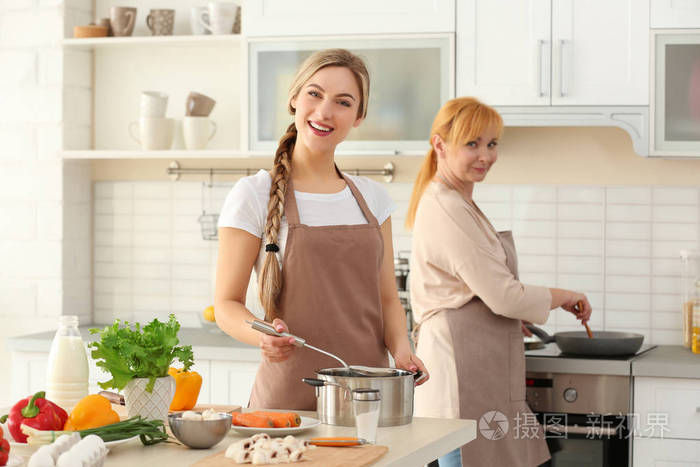 年轻的妇女和她的母亲在厨房做饭