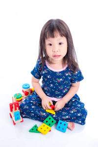 小的亚洲女孩玩木制火车玩具白色