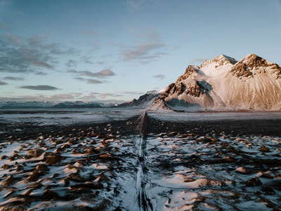 在冰岛 Stokksnes, 一条通向高山的道路, 覆盖着积雪。照片是用无人机拍摄的