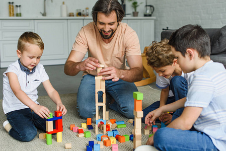 快乐的父亲和孩子们一起在地板上玩木块