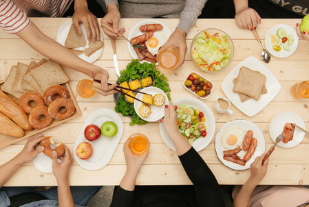 享受与朋友共进晚餐。顶视图的一群人一起坐在木桌吃饭