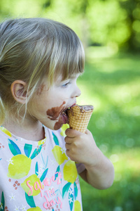 美丽的女孩吃巧克力冰淇淋在阳光明媚的夏天天