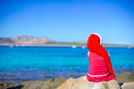 可爱的小女孩，在圣诞老人在圣诞海滩度假期间的帽子