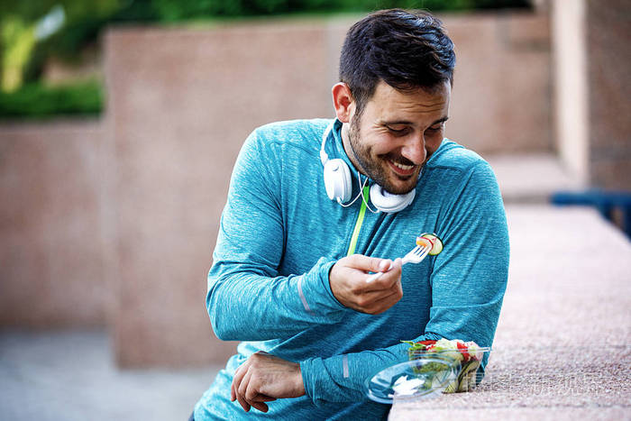 年轻英俊的男人慢跑后享受蔬菜沙拉