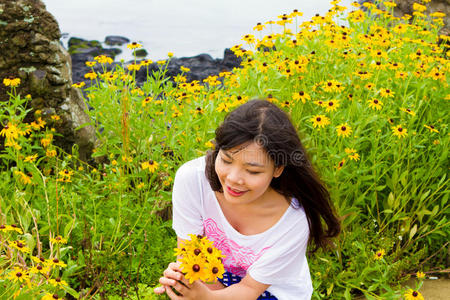 女孩坐在海边的雏菊向日葵地里