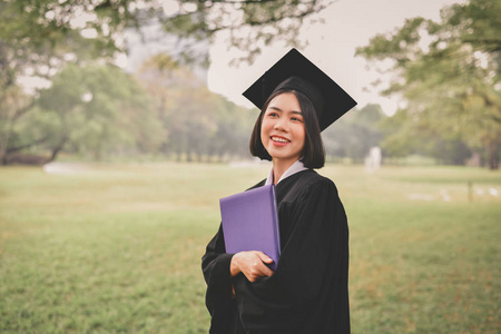 毕业概念。毕业日毕业的学生。亚洲学生在毕业典礼上开心地微笑。学生在花园里穿毕业礼服