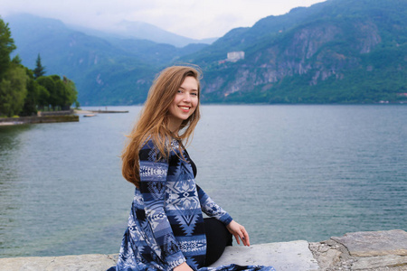 年轻女子坐在山莫湖附近, 阿尔卑斯山在背景