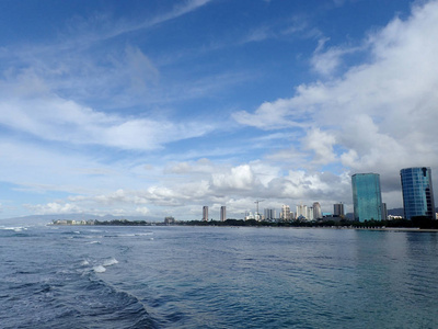 在夏威夷瓦胡岛的一个美丽的日子里, 莫阿纳海滩的水中有公寓建筑和建筑起重机在远处的波浪中。