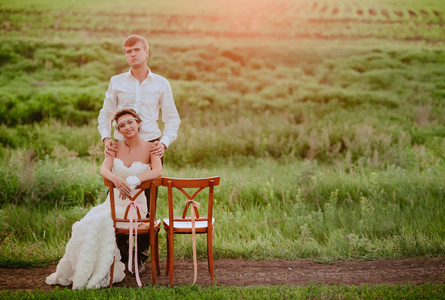 年轻貌美的新娘和新郎坐椅子在夕阳的光
