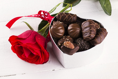 红玫瑰，盒巧克力白色木制背景上