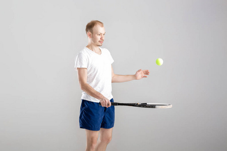 年轻的网球运动员打网球在灰色的背景上