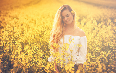 在日落时微笑黄色油菜花田的女人