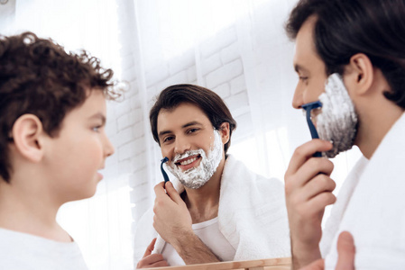 小儿子看起来像父亲刮胡子用剃刀