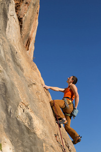 年轻的男登山者悬挂在悬崖上