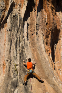 年轻的男登山者悬挂在悬崖上