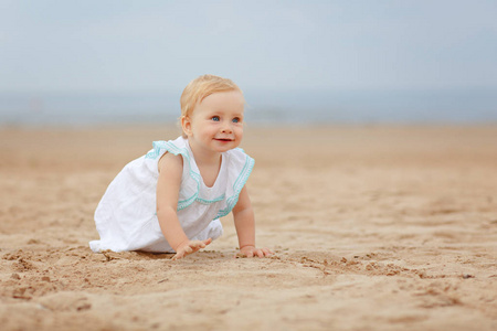 迷人的小女孩坐在海边的沙滩上在夏天