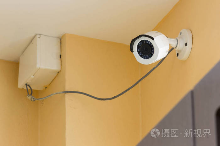 在室内的橙色水泥墙上运行的闭路电视监控摄像头