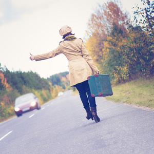 优雅的女人与一个手提箱旅行公路