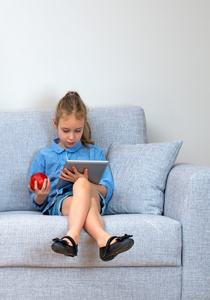 小女孩坐在沙发上，使用 tablet pc。您的文本的空间