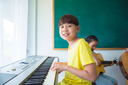 小亚洲男孩在学校演奏音乐键盘