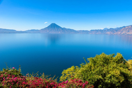 从湖阿特蒂兰湖的看法在清晨, 蓝色天蓝和清澈的水, 美丽的魔法湖与火山和土著居民在危地马拉高地图片采取接近巴哈契最旅游城市那里