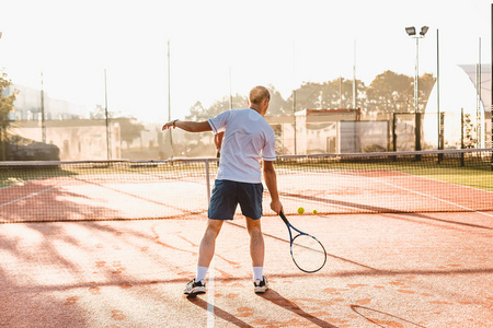 早上在阳光下打网球的男人