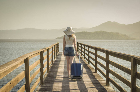 伟大的度假理念。年轻的妇女拿着她的手提箱, 等待船在码头上