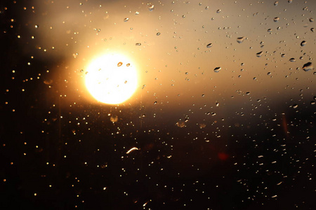 在夕阳的模糊背景下, 玻璃上的雨滴的宏观摄影。深色和橙色色调的纹理