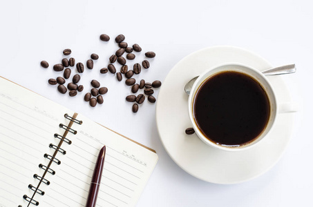 咖啡豆和杯咖啡上白色带笔记本和笔