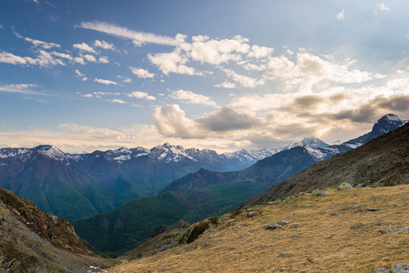 最后的温暖阳光上高山河谷与发光的山峰和风景秀丽的云。意大利法国阿尔卑斯山，夏天的旅游目的地