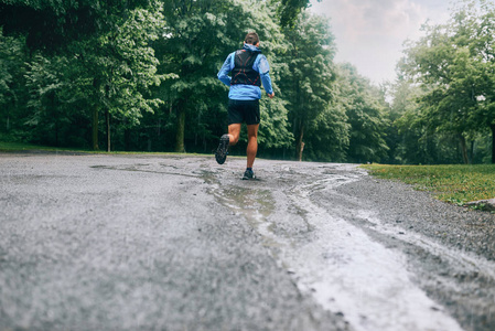 肌肉的犊牛的健康男性慢跑训练跨国家森林小道赛跑在雨中对自然教育径