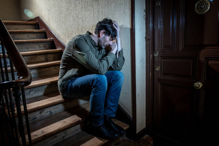 沮丧的拉丁人坐在手里在楼梯间感到孤独和悲伤, 并强调工作和生活在一个心理健康概念