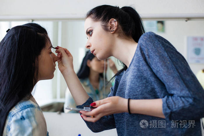 后台的场景: 专业化妆师做镜子附近上班的魅力模型化妆
