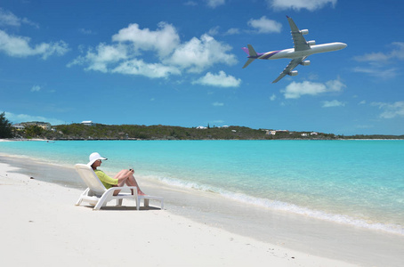 太阳帽上的年轻女子照片在大埃克苏马的沙滩上放松, 巴哈马与飞机在蓝天上