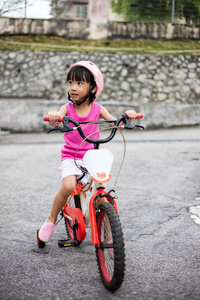 亚洲中国的小女孩骑着自行车在柏油马路上