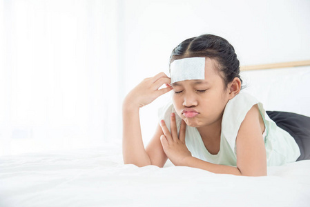 年轻的亚洲与凉爽的凝胶在额头上头痛躺在床上