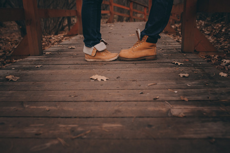 年轻的情侣穿着靴子在木桥上户外行走