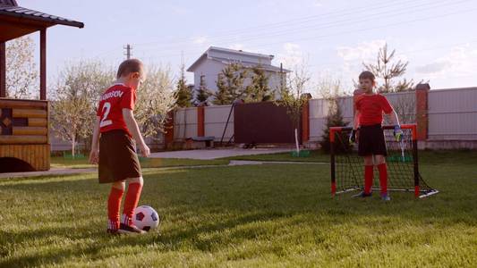 小男孩在后院的草坪上踢足球。