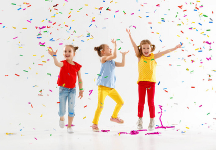 快乐的孩子在假日跳跃在多彩多姿的五彩纸屑上
