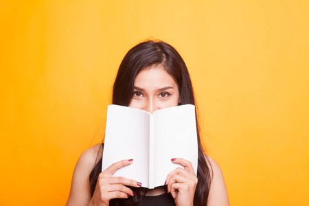 年轻的亚洲妇女头疼读一本关于黄色背景的书