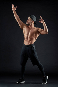 肌肉运动的男子在黑色背景下摆姿势