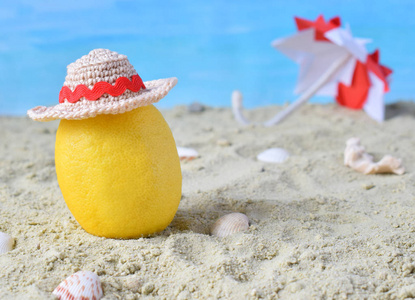 创意极小的夏日创意。柠檬柑橘时髦的竹帽和沙滩伞上的沙子。热带海滩概念。创意艺术。复制空间