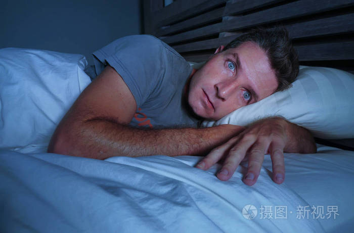 焦躁不安的年轻有吸引力的男人睡在床上睡不着 睁大眼睛睡不着觉失眠